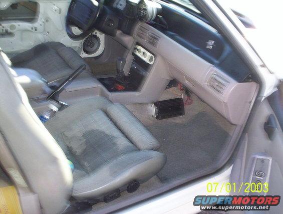Interior of a 1991 Ford Mustang, showing seats, dashboard, steering wheel, and center console