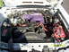 1991 Ford Mustang - The engine bay of a 1991 Ford Mustang shows a modified engine with purple valve covers and a red battery.