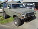 1978 Ford Bronco - A 1978 Ford Bronco with a matte olive green paint job and off-road tires sits in a driveway next to another truck.