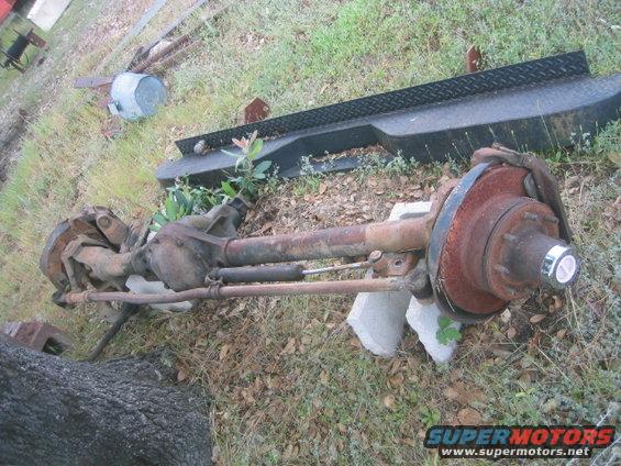 Truck rear axle assembly with drum brakes and shock absorber, resting on concrete blocks