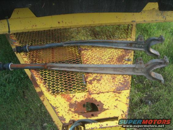 Two rusty suspension control arms on a yellow trailer