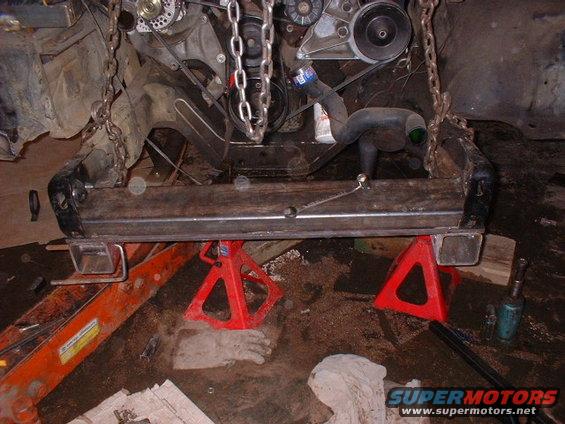 Engine hoisted by chains, supported by jack stands under the frame