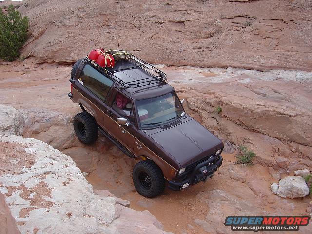 Brown 1986 Ford Bronco II climbing rocks with gas cans on roof rack