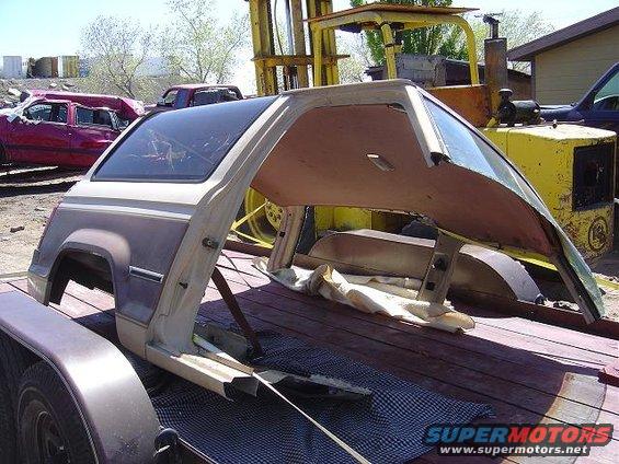 1986 Ford Bronco II body shell, disassembled, on a trailer. Other vehicles and equipment in background