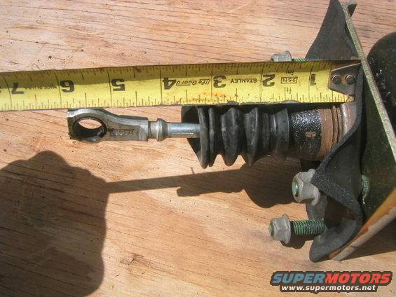 Brake master cylinder measured with a yellow tape measure on a wooden surface