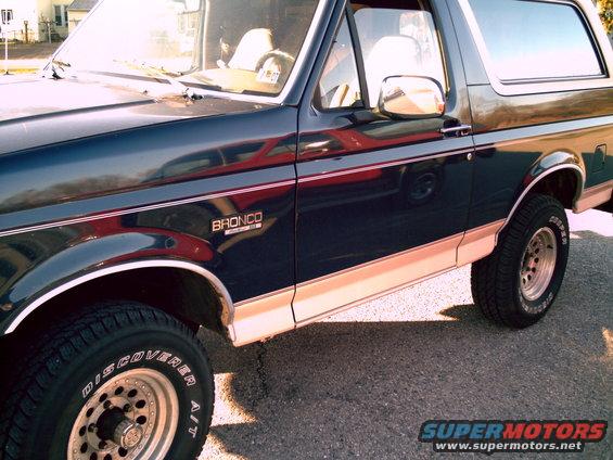 Dark blue 1993 Ford Bronco with tan lower trim, chrome wheels, and "Bronco" badge on the front fender