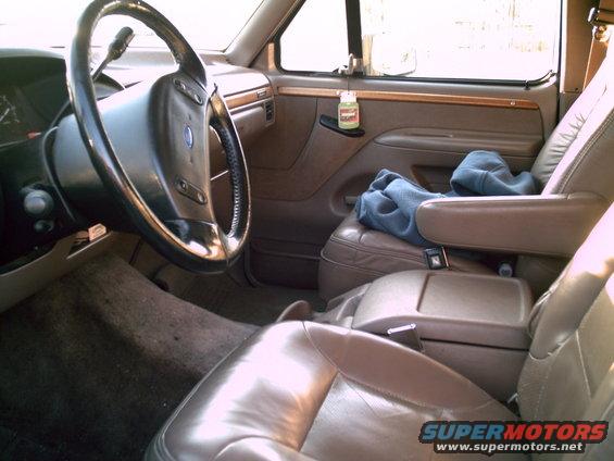 Interior shot of a truck's driver side, showing the steering wheel, dashboard, and passenger seat with a blue sweatshirt on it