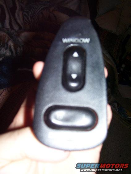 Hand holding a black power window switch with up and down arrows and a lock button. Text reads 'WINDOW'
