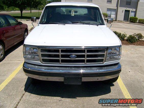 White Ford Bronco front grille and headlights, parked in a lot