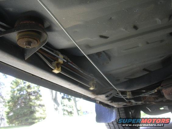 Underside view of vehicle showing brake lines and fuel lines running along the frame rail