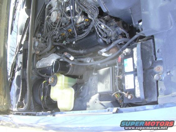 Engine bay showing battery, coolant reservoir, and engine components