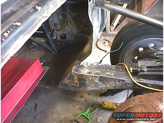 Vehicle chassis with exposed wiring and a wheel, undergoing repair