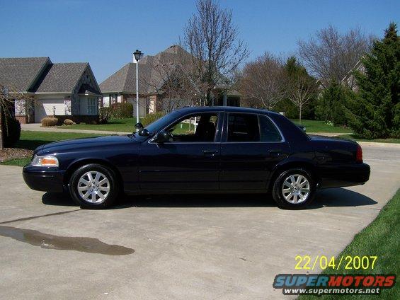 2003 Ford Crown Victoria parked on a concrete driveway in front of houses