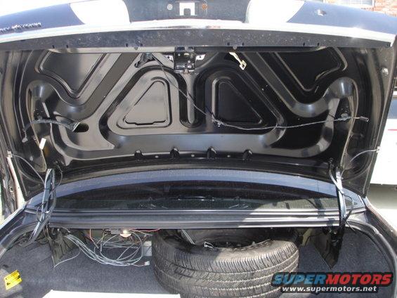 Trunk interior showing spare tire, wiring, and hood hinges