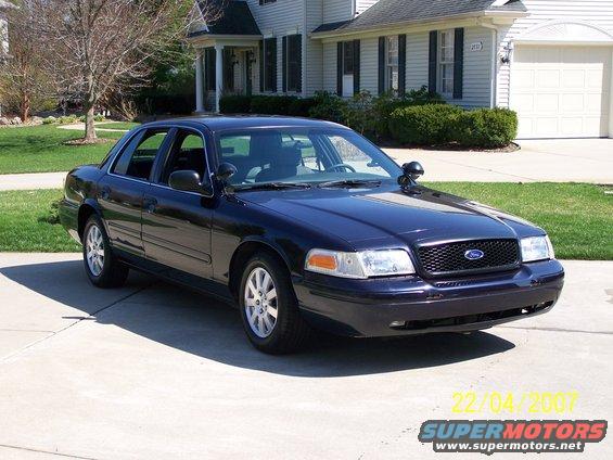Dark blue 2003 Ford Crown Victoria parked in a driveway in front of a house