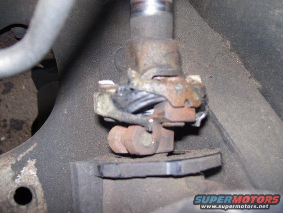 Close-up of a rusty suspension part with a metal rod and some wiring