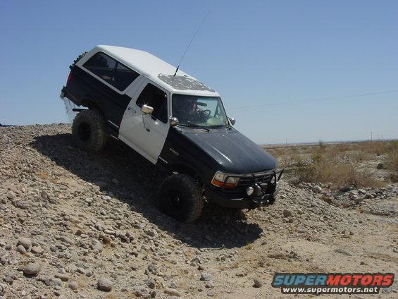 1994 Ford Bronco climbing a rocky incline with a two-tone paint job