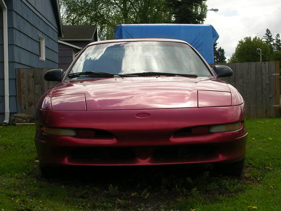 Front view of a red 1996 Ford Probe parked in a grassy yard