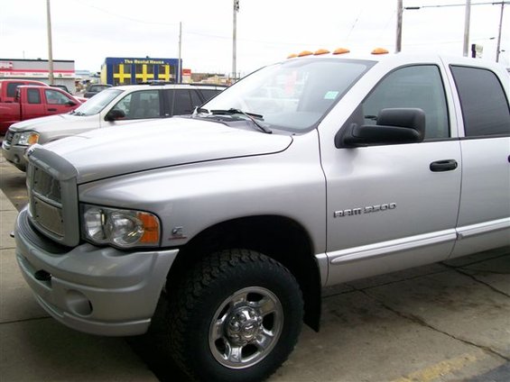 Silver Dodge Ram 3500 pickup truck parked outside with other vehicles