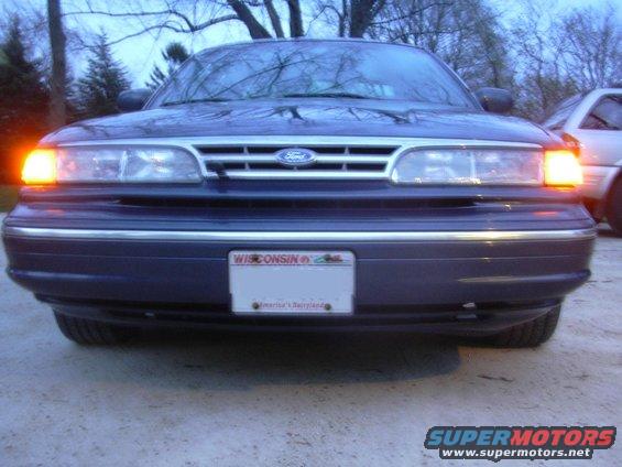 Front view of a dark blue Ford Crown Victoria with its left turn signal on. Wisconsin license plate visible