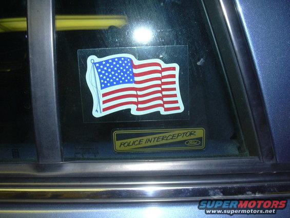 Car window with American flag sticker and a 'Police Interceptor' Ford badge