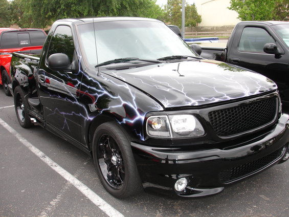 Black Ford F-150 Lightning pickup truck with lightning bolt graphics, custom grille, and aftermarket wheels