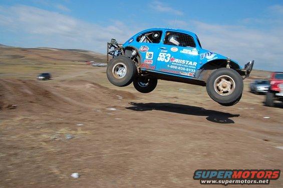 Blue off-road buggy airborne, number 553, with sponsor logos