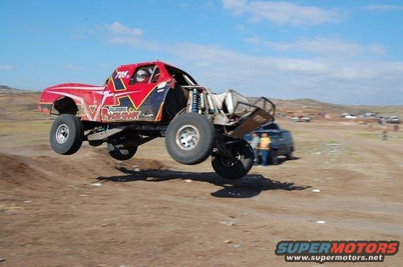 Red off-road truck mid-air, with "RACE CRAFT" text and number 705 visible