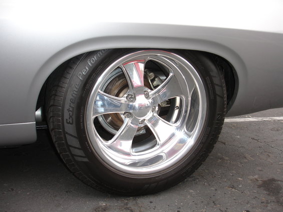 Close-up of a chrome five-spoke wheel and tire on a silver car's rear fender