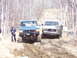 1996 Ford Bronco - A green 1996 Ford Bronco and a GMC truck navigate a challenging muddy off-road trail.