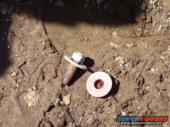 Bolt with washer and a pink washer on dirt ground