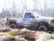 1996 Ford Bronco - A pickup truck is stuck in the mud, with its tires submerged in the mire.
