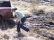 1996 Ford Bronco - A woman stands near a red pickup truck that is stuck in a muddy, grassy field.