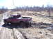 1996 Ford Bronco - Pickup truck is stuck in the mud on a dirt road with trees in the background.