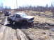 1996 Ford Bronco - Two trucks navigate a challenging muddy off-road course on a bright, overcast day.