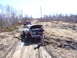 1996 Ford Bronco - A GMC truck is stuck in the mud with its hood open, while another truck is visible in the background.