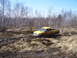 1996 Ford Bronco - A yellow pickup truck is stuck in the mud with trees in the background.