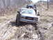 1996 Ford Bronco - A GMC truck is stuck deep in the mud on an off-road trail, with another vehicle and people visible further up the hill.