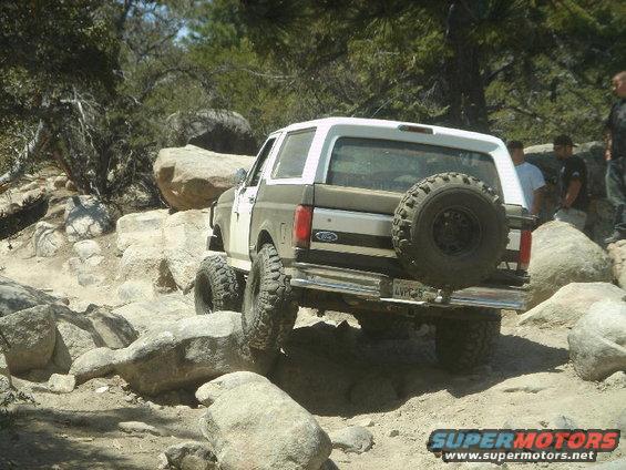 1994 Ford Bronco navigating a rocky trail, rear view with spare tire mounted
