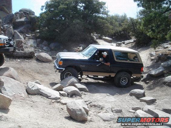 Dark blue and tan Ford Bronco navigating a rocky off-road trail