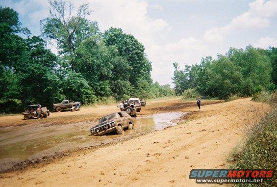 1978 Ford Bronco stuck in mud with other off-road vehicles nearby