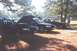 2002 Ford Crown Victoria - A dark 2002 Ford Crown Victoria is parked with its hood open, alongside other vehicles in an outdoor setting.