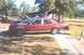2002 Ford Crown Victoria - Red sedan parked on a sidewalk with trees and a building in the background.