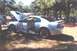 2002 Ford Crown Victoria - A silver coupe, possibly a Ford Mustang, is parked outdoors with its hood and driver's door open.