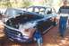 2002 Ford Crown Victoria - A man stands next to a heavily customized vintage sedan with its hood up, parked outdoors.