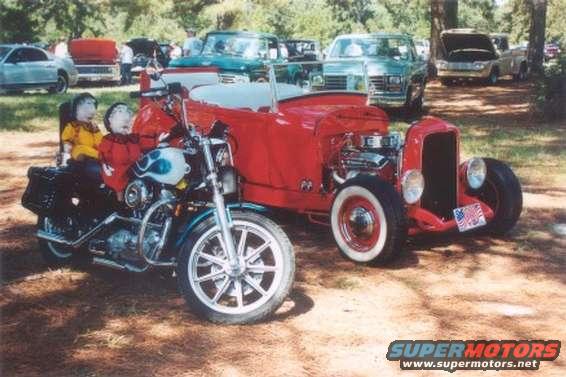 Motorcycle with two dolls and a red hot rod car with a license plate