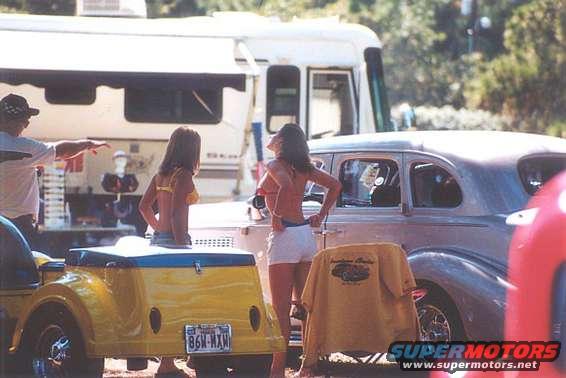Yellow trailer with license plate 86W-MXN, vintage car, two women, and RV
