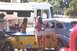 2002 Ford Crown Victoria - A vintage car is parked next to an RV and a yellow trailer, with two women nearby.