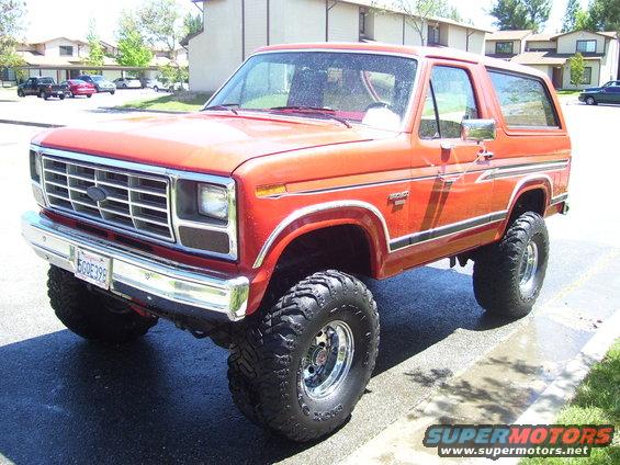 Orange Ford Bronco with lifted suspension and off-road tires, parked on a street