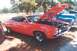 2002 Ford Crown Victoria - A red 1970s muscle car is parked with its hood open, revealing the engine, with a blue truck visible behind it.